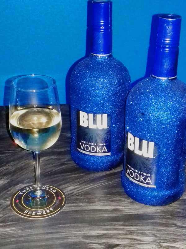Two bottles of Blu vodka with a glass of wine